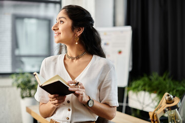 Young indian woman engrossed in reading a book in a modern office setting.