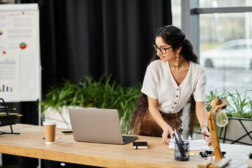 Young indian woman energetically works at desk with laptop.