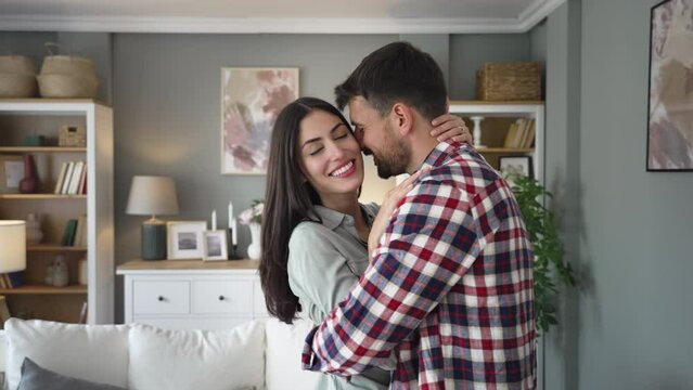 Young happy newlywed couple, man and woman, dancing in their new home. Emotional dance of just married couple husband and wife moved in their new apartment to start new life together. Love and respect