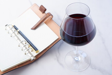 赤ワインを飲みながら、リング式のシステム手帳に日記をつける
