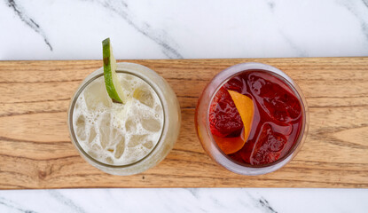 Cocktails. Top view of a tropical Caipirinha drink with ice and lime, and a Negroni cocktail with...