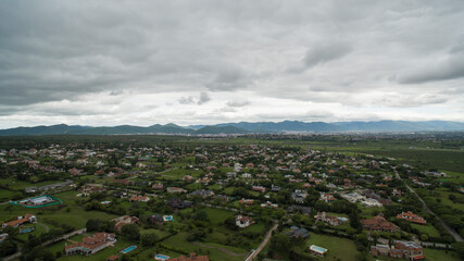 Aerial panoramic view of the town in the countryside at the foot of the mountains under a dramatic sunset sky with clouds