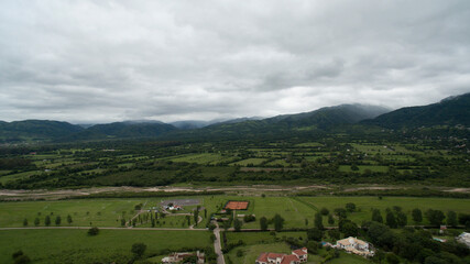 Aerial view of a private neighborhood in the suburbs at the foot of the hills in Salta. View of the green field and forest under a cloudy sky. 