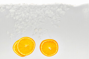 Textured photo of glass of water with ice in which add slices of sweet and sour citrus fruit,...