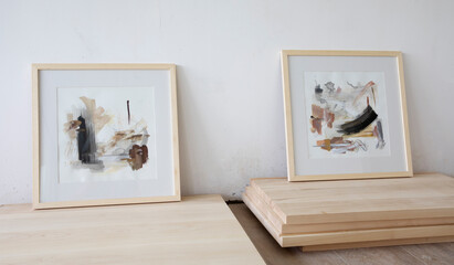 Modern art. Closeup view of contemporary abstract paintings with a wooden framing, in the art studio. Beautiful brushwork, texture and pale color pattern.	