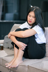 Sad and depressed young female sitting on the sofa, sad mood, feel tired, lonely and unhappy concept.
