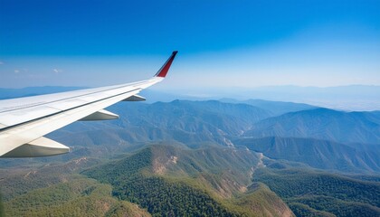 A view across a wing of a commercial plane flying over the blue mountains
