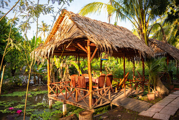 Wooden gazebo with palm tree leaves roof in tropical forest