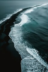 Aerial photography of the ocean waves breaking on black sand beach