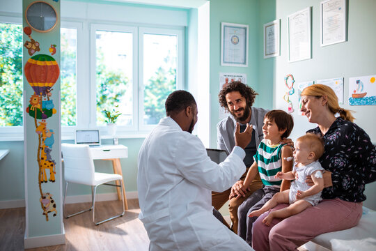 Family at pediatrician's office for children's check-up with doctor