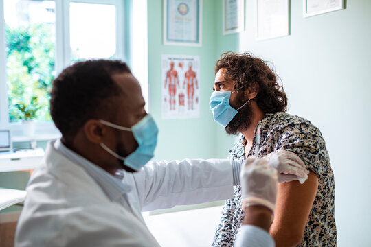 Doctor administering a vaccine to a male patient in a medical office