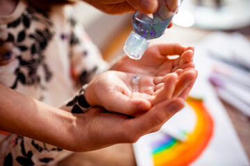 Mother giving daughter hand sanitizer while doing crafts at home