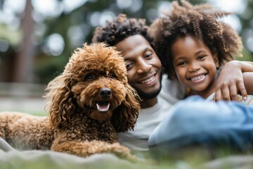 A joyful father and daughter posing playfully with a delightful brown dog on the grass, looking at...