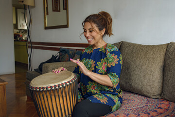 An Adult Happy Woman expressing herself through African music with a Djembe drum.