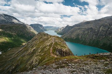 Group of People Trekking Through the Mountains of Jotunheimen National Park with a Lake in the Background, on the Way to Memurubu During Their Tourist Trip in Norway