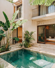 A modern minimalist house in Mexico with a small pool and garden near the home featuring lush plants, concrete floors, beige walls creating a tropical vibe
