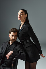 A man and a woman in elegant attire pose gracefully together.