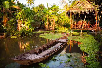 Old wooden rowing boat in pond with wooden gazebo