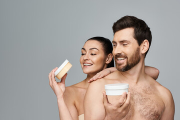 Jolly couple elegantly hold a jar of cream, showcasing their skincare routine.