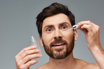 Attractive man applying serum on his face.