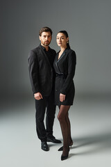 Elegant couple in love, standing close in stylish attire.