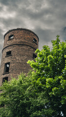 Minsk, an old brick tower in the city, cloudy sky, a growing tree