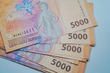 Indonesian currency isolated on a white background. The 5,000 rupiah banknote features a new design.
