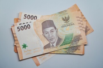Indonesian currency isolated on a white background. The 5,000 rupiah banknote features a new design.