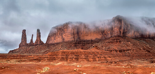 Wide panorama of famous Three Sisters in Monument Valley and the accompanying mountain range during...