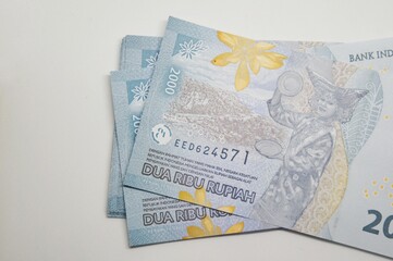 Close-up of Indonesian 2000 Rupiah banknotes scattered on a white background. Financial concept
