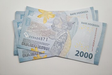 Close-up of Indonesian 2000 Rupiah banknotes scattered on a white background. Financial concept