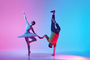 Artistic Dance Synergy. Beautiful young ballerina in tradition tutu and pointe dancing with man, break dancer against gradient background in neon light. Classical and modern dance, performance concept