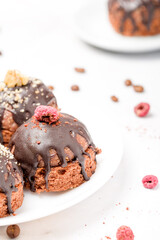 Round chocolate cakes. Decorated with candied raspberries. Light background
