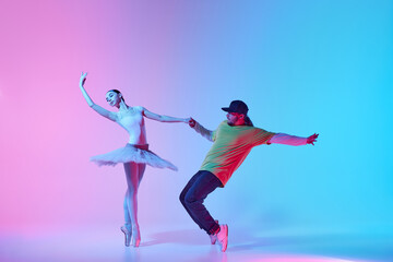 Tender young girl, beautiful ballerina dancing in tutu on pointe with energetic man, break dancer n...
