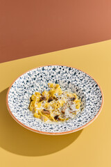 Delicious Fettuccine Pasta with Mushrooms and Creamy Sauce in a Decorative Bowl on Colorful...