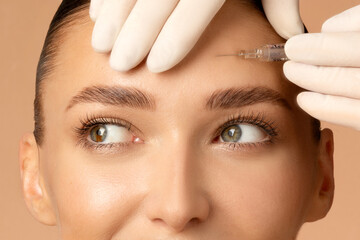 Closeup shot of young Caucasian woman getting beauty cosmetic injection in forehead, beautiful lady getting anti-aging treatment