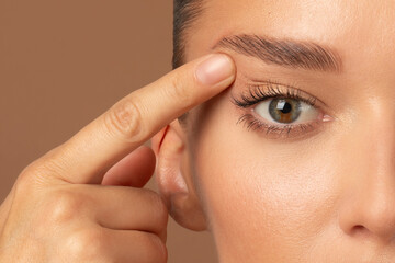 Closeup of young European woman pointing to the wrinkles on the upper eyelid, touching face....