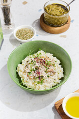Mushroom Risotto with Fresh Herbs in a Green Bowl on Marble Table Enhanced with Condiments and Light Highlights