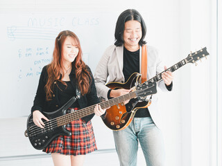 joyful duo Asian artist rock band of young girl idol on bassist and male on semi-hollow electric guitar standing on white background for music, artist..