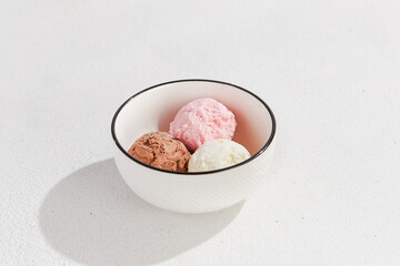 Delicious Trio of Ice Cream Scoops: Vanilla, Strawberry, and Chocolate in a White Bowl