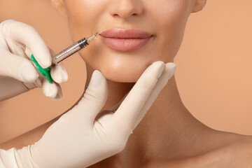 Lip augmentation concept. Unrecognizable lady receiving hyaluronic acid injection, posing on beige...