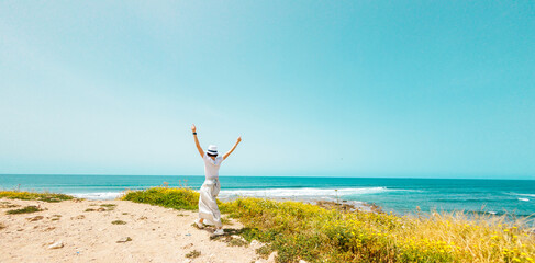 relaxation on the beach. happy girl walks along the beach. A young happy woman in a white dress...