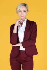 Portrait of young businesswoman smiling and raise her hand to the chin over yellow background