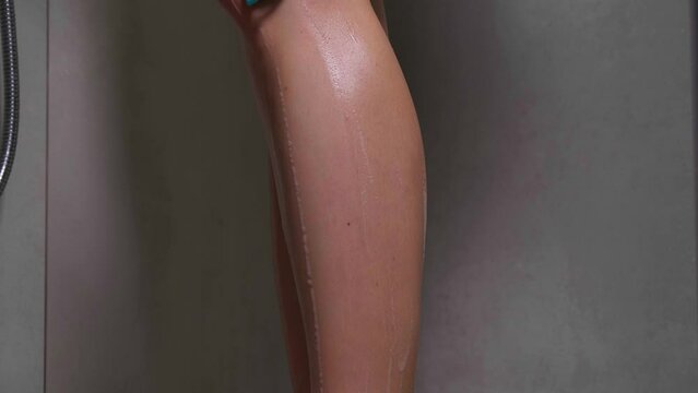 Woman shaving legs while taking shower, closeup