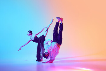Ballerina and breakdancer dancing against gradient background in neon light, highlighting beauty of mixed dance styles. Concept of classical and modern dance, performance