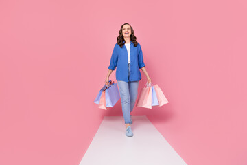 Full length photo of lovely senior lady walk podium hold shopping bags dressed stylish blue garment isolated on pink color background