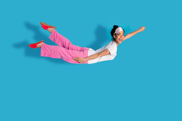 Full size photo of nice young woman fly empty space wear pajama isolated on blue color background