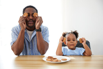 portrait father and daughter showing chocolate cookies on the table