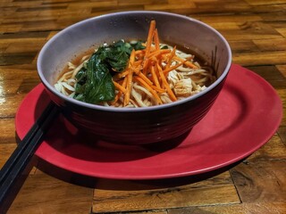 Asian noodle soup, ramen or curry mie with meat, chives, vegetables and egg in bowl