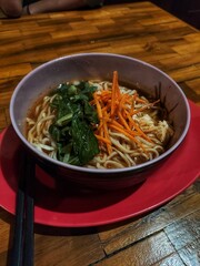 Asian noodle soup, ramen or curry mie with meat, chives, vegetables and egg in bowl
